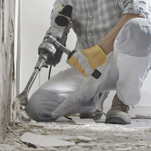Nahaufnahme: Handwerker entfernt mit dem Meißelhammer alten Belag