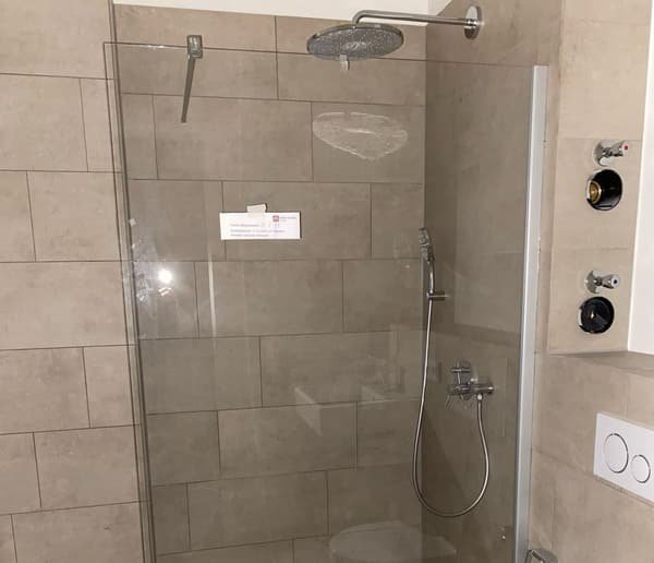 Fertiges Badezimmer mit bodengleicher Dusche und großformatigen Fliesen
