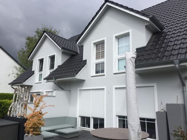 Von S&M Bauwerk saniertes Einfamilienhaus mit heller Fassade und dunklem Ziegeldach