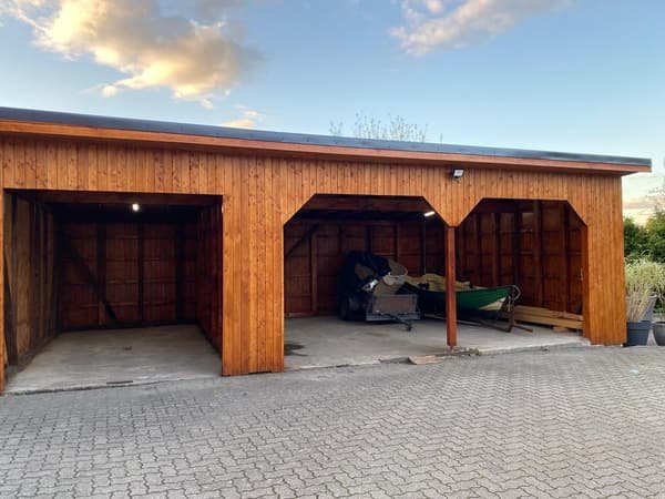Dreifeld-Carport aus Holz mit dunkler Dachkante im Abendlicht